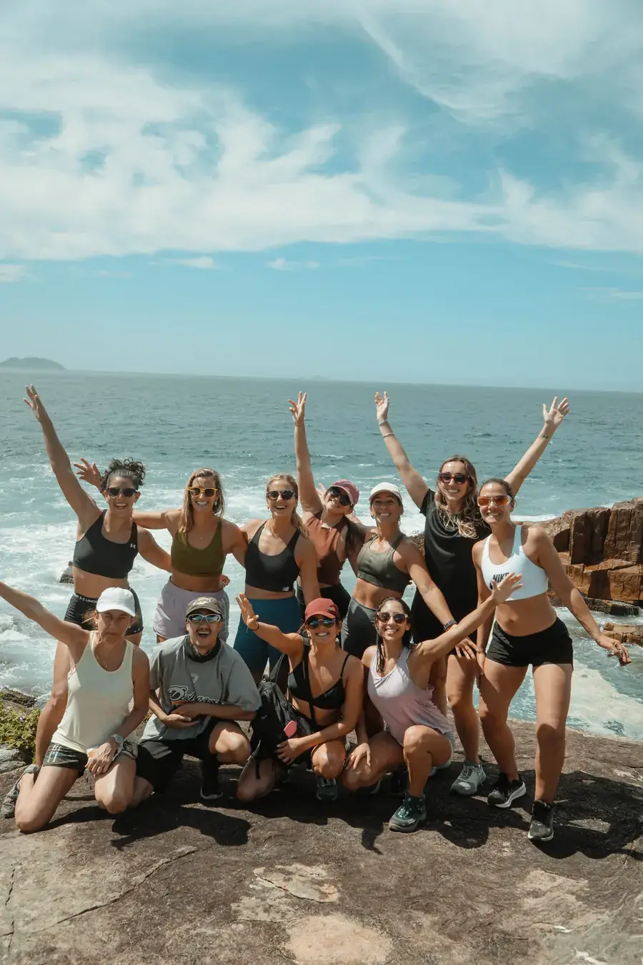 Grupo de viajeros en la cima de un cerro con vista al mar